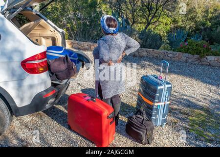 Mode de vie et de voyage concept : femme dos valises de chargement dans la voiture Banque D'Images