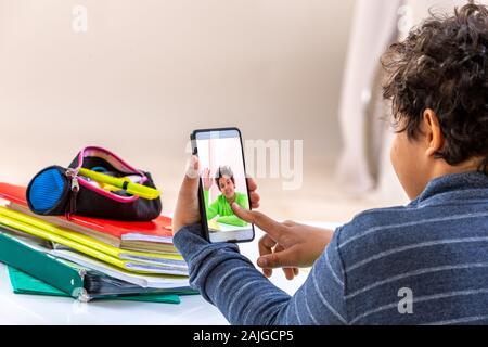 Garçon étudiant avec smartphone les distraire de l'étude. jeu de l'adolescence à la maison au lieu de faire ses devoirs Banque D'Images