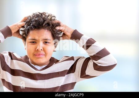 Garçon de stress se grattant les cheveux avec de l'expression confuse Banque D'Images