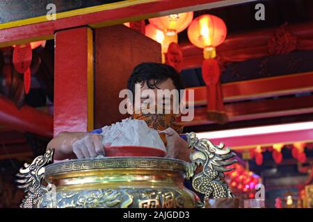 Un homme nettoie les cendres d'encens d'un hio-lo dans un temple bouddhiste. Ce rituel annuel avant la célébration du nouvel an chinois s'appelle le rituel d'Ayak Abu. Banque D'Images