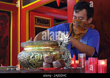 Un homme nettoie les cendres d'encens d'un hio-lo dans un temple bouddhiste. Ce rituel annuel avant la célébration du nouvel an chinois s'appelle le rituel d'Ayak Abu. Banque D'Images