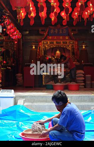 Un homme nettoie les cendres d'encens d'un hio-lo dans un temple bouddhiste. Ce rituel annuel avant la célébration du nouvel an chinois s'appelle le rituel d'Ayak Abu. Banque D'Images