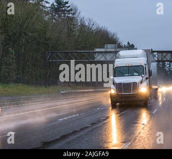 Big Rig de qualité industrielle classique semi transport camion transportant du fret commercial dans la région de dry van semi-remorque de la conduite sur route humide soirée de pluie w Banque D'Images