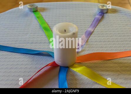 Bougies avec des liens de couleur sur une table avec nappe en papier blanc Banque D'Images