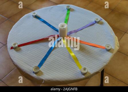 Bougies avec des liens de couleur sur une table avec nappe en papier blanc Banque D'Images
