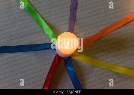 Bougies avec des liens de couleur sur une table avec nappe en papier blanc Banque D'Images