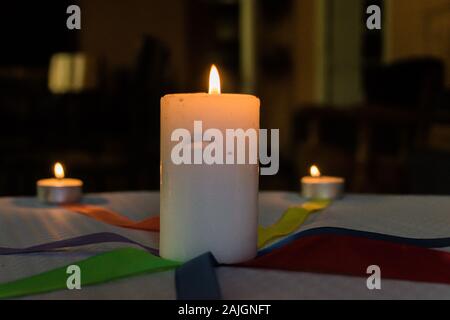 Bougies avec des liens de couleur sur une table avec nappe en papier blanc Banque D'Images