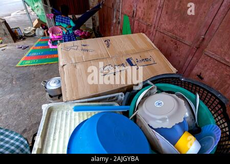 Vaisselle mains près de boîtes en carton qui servent de brise-vent pour poêles à bois utilisé pour cuire les aliments par les détritivores pauvres à leur abri à Kampong Cham, au Cambodge. Banque D'Images