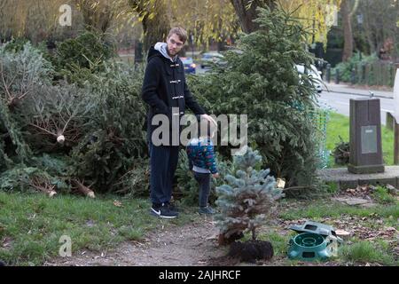Un homme se tient avec son enfant à côté d'Hampstead Heath Tree recycler repas le samedi, 4 janvier 2020, 04/01/2020 Banque D'Images