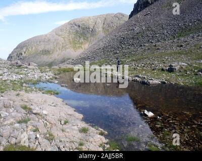 Lone Man Walking in sur Bealach Mor au-dessous de la montagne écossaise Corbett Fuar Tholl, Strathcarron, Highlands, Ecosse, Royaume-Uni. Banque D'Images