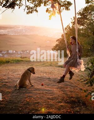 Adorable jeune fille jouant avec son chien mignon sur la nature pendant le coucher du soleil Banque D'Images