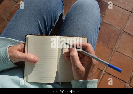 Femme avec un ordinateur portable blanc, stylo à la main Banque D'Images