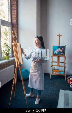 Happy young woman wearing apron dans le studio Banque D'Images