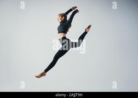 Poser sporty woman jumping in studio contre blanc couleur arrière-plan. Belle jeune fille en sautant moment Banque D'Images