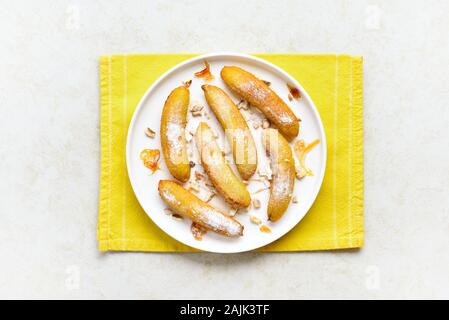 Bananes frits sur plaque sur fond noir en lumière. De savoureux dessert de bananes poêlées au style asiatique. Haut de la vue, télévision lay Banque D'Images