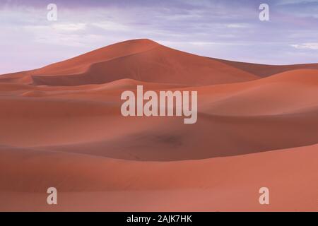 Paysage désertique de dunes de sable au coucher du soleil Ciel près de Merzouga, Maroc, Afrique. La découverte et l'aventure travel concept. La lumière du soleil sur les dunes du désert. Banque D'Images