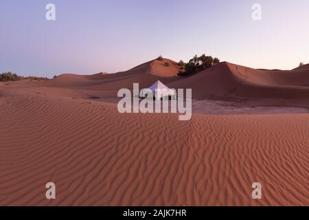 Camp avec tente dans le désert entre les dunes de sable. Journée ensoleillée dans le Sahara pendant une tempête de sable au Maroc concept fond nature pittoresque Banque D'Images