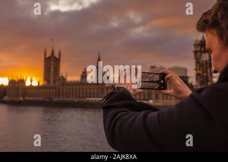 Westminster, Londres, 4 janvier 2020. Un homme s'enclenche sur le coucher du soleil. Les touristes londoniens et profiter du magnifique coucher de soleil sur le pont de Westminster et le Parlement, dans l'arrière-plan. Calme et sec à Londres à la fin d'une belle journée ensoleillée à travers la capitale. Banque D'Images