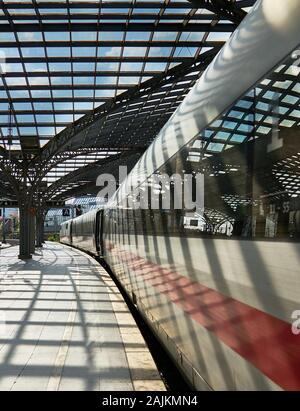 La lumière et les ombres intéressantes du toit en verre de la gare centrale de Cologne sont jelées sur un train interurbain à grande vitesse ou DE LA GLACE à la plate-forme. Banque D'Images