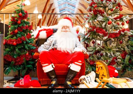 TALLINN, ESTONIE - le 22 décembre 2019 : le père Noël se trouve entre les sapins décorés dans Balti Jaam market bulding dans Tallinn Estonie en décembre 2019 Banque D'Images