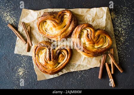 Brioches à la cannelle parfumée fraîche de boulangerie. Des pâtisseries traditionnelles sur fond sombre. Style rustique. Banque D'Images