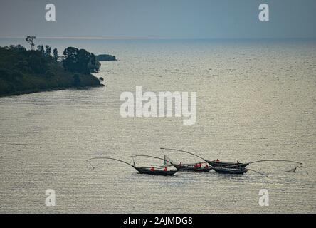 Pêche des canoës sur le lac avec la réflexion du soleil sur l'eau. Lac Kivu, Rwanda. Le lac Kivu est partagé par le Rwanda et la République démocratique du Congo. Banque D'Images