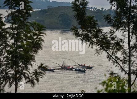 Pêche des canoës sur le lac avec la réflexion du soleil sur l'eau. Lac Kivu, Rwanda. Le lac Kivu est partagé par le Rwanda et la République démocratique du Congo. Banque D'Images