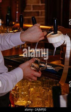 Bartender pouring Projet de la bière à partir de la grue dans le verre dans un pub. Banque D'Images