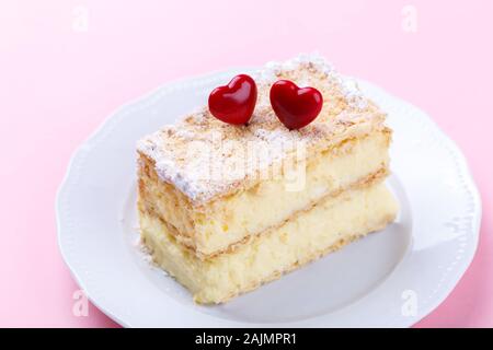 Mille feuille français avec crème vanille gâteau décoré avec des coeurs sur fond rose pour la Saint-Valentin Banque D'Images