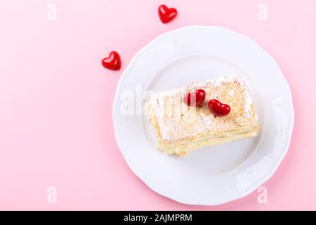 Mille feuille français avec crème vanille gâteau décoré avec des coeurs sur fond rose pour la Saint-Valentin, vue du dessus Banque D'Images