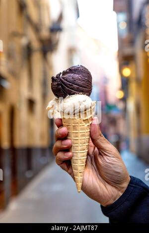 Main tenant au chocolat végétalien et Majorquin amande glace dans un cône d'Iceberg La Llonja, Mallorca, Espagne Banque D'Images