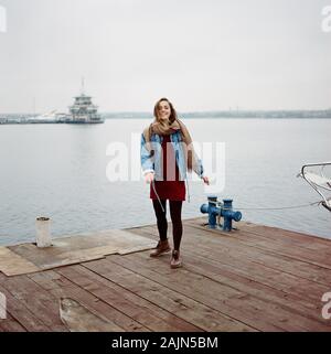 Femme élégante en robe rouge et bleu l'article sur l'ancienne jetée en bois avec un bateau Banque D'Images