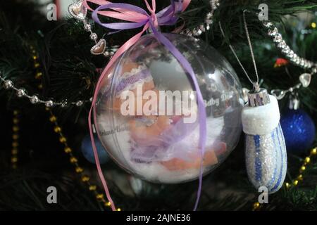 Little baby doll en boule de cristal avec des rubans colorés pour la décoration sur les vacances d'hiver, ou un cadeau pour les filles Banque D'Images