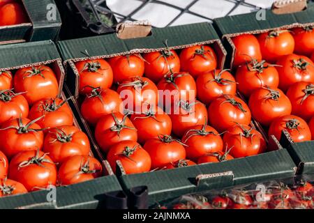 Beaucoup de tomates dans des boîtes. De belles tomates rouges en vente Banque D'Images