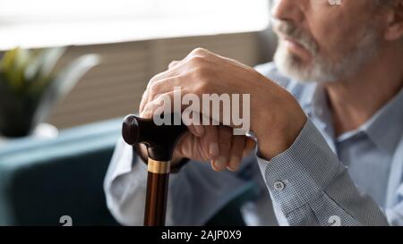 Vieil homme assis à l'intérieur libre de se concentrer sur les mains tenant la canne à sucre Banque D'Images