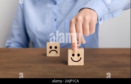 Le meilleur score excellents services d'affaires. Main d'un businessman choisit un smiley sur une cale en bois cube, panorama, copy space Banque D'Images