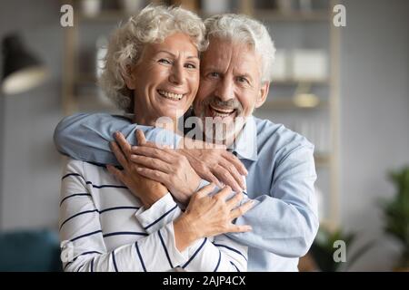 Personnes âgées de 65 ans couple in love embrassant sourire regarder camera Banque D'Images