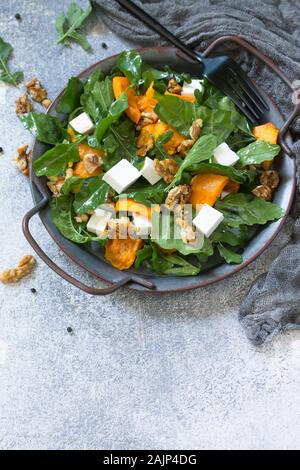 Notion de régime, l'alimentation végétalienne. Avec salade de potiron cuit, feta, fromage et vinaigrette légère sur fond de pierre. Espace libre pour votre texte. Banque D'Images