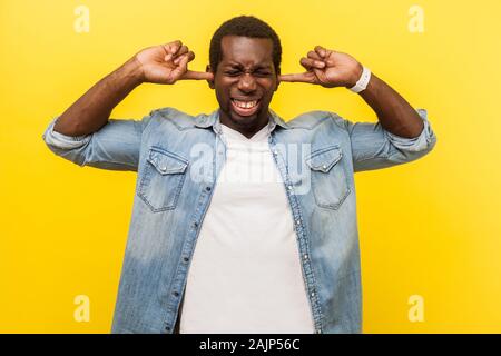 Ne veulent pas entendre. Portrait de l'homme irrité frustrés en denim chemise décontractée couvrant les oreilles avec expression ennuyé, ignorant les conflits ou la pression. je Banque D'Images