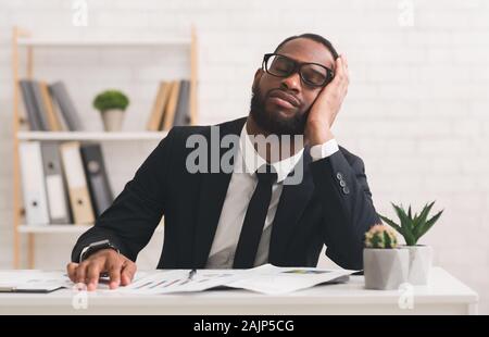 Jeune homme noir fatigué dans les verres ayant pan sur lieu de travail, la surcharge de travail, copy space Banque D'Images
