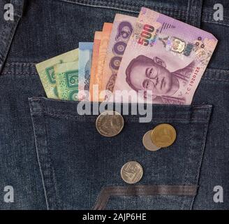 De nombreux billets et pièces de bahts en Thaïlande dans l'arrière poche de jean bleu comme une image Vue de dessus close up Banque D'Images
