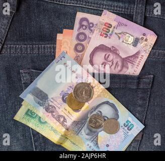 De nombreux billets et pièces de bahts en Thaïlande dans l'arrière poche de jean bleu comme une image Vue de dessus close up Banque D'Images