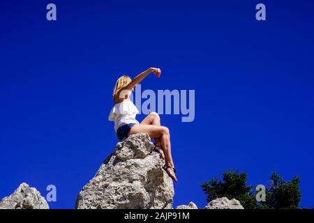 Femme blonde'admire la vue alors qu'il était assis sur un rocher sur la montagne (l'Ainos Ainos) sur l'île grecque de Céphalonie, Mer Ionienne, Grèce avec un b Banque D'Images