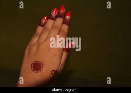 Close up of main gauche de girl with red vernis à ongles et les dessins et modèles industriels dans mehndi doigts et milieu de la main, l'accent sélective Banque D'Images