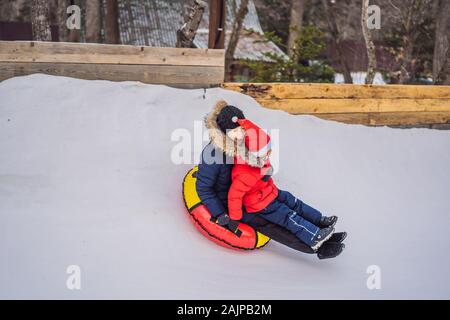 Maman fils monter sur une luge hiver gonflable tube. Plaisir d'hiver pour toute la famille Banque D'Images