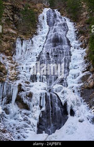 Paysage d'hiver avec cascade de montagne sur les bords gelés Banque D'Images