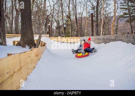 Maman fils monter sur une luge hiver gonflable tube. Plaisir d'hiver pour toute la famille Banque D'Images