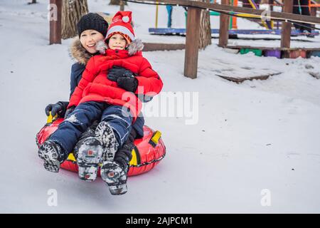 Maman fils monter sur une luge hiver gonflable tube. Plaisir d'hiver pour toute la famille Banque D'Images