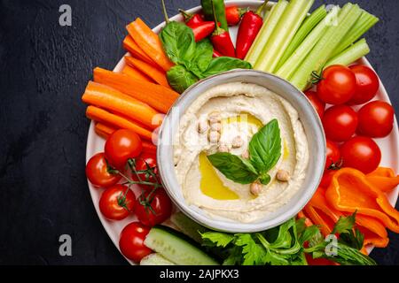 L'hoummos plat avec un assortiment de collations. Dans un bol à l'hummus et légumes bâtonnets. Plaque avec moyen-orientales. Parti, finger food. Vue d'en haut. Trempette à l'hummus, Végétalien Banque D'Images