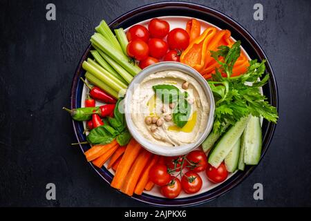 L'hoummos plat avec un assortiment de collations. Dans un bol à l'hummus et légumes bâtonnets. Plaque avec moyen-orientales. Parti, finger food. Vue d'en haut. Trempette à l'hummus, Végétalien Banque D'Images